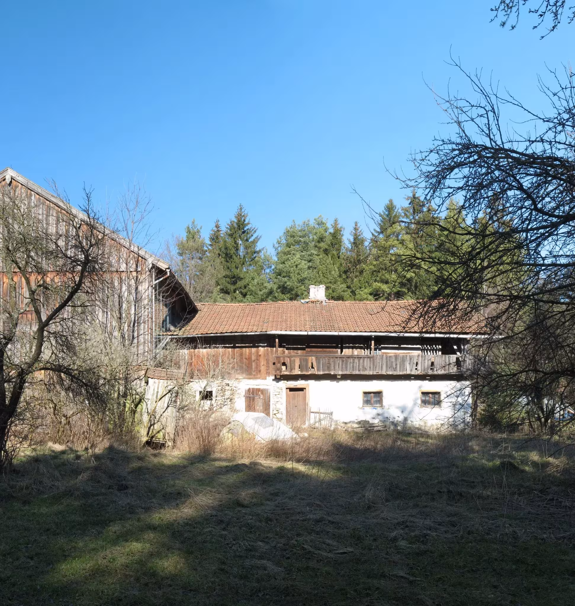 Granja bávara en ruinas antes de la intervención, con fachada encalada y cuadra de madera