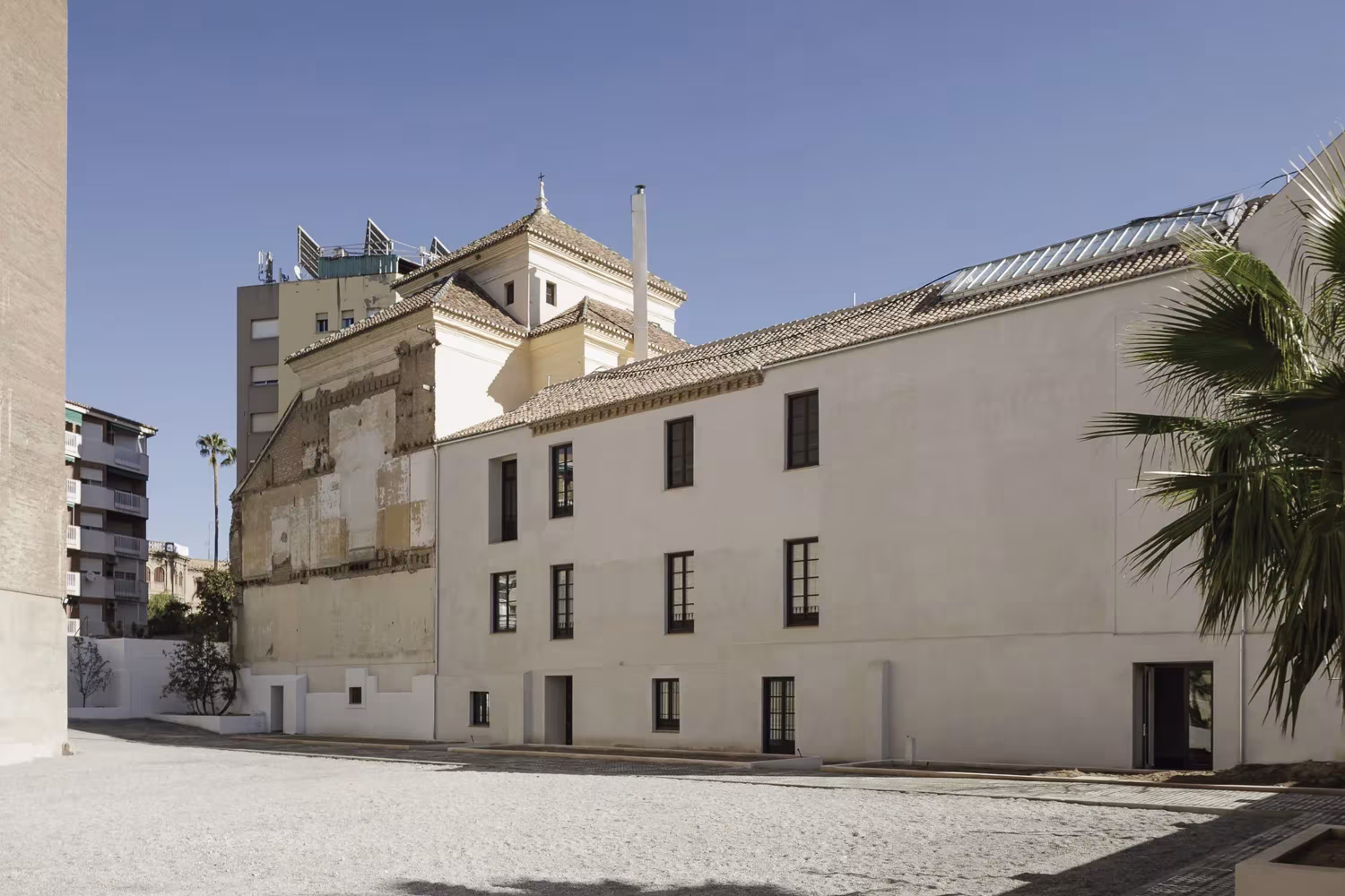 Fachada exterior del antiguo convento del siglo XVII rehabilitado por Elisa Valero en Granada, con una palmera