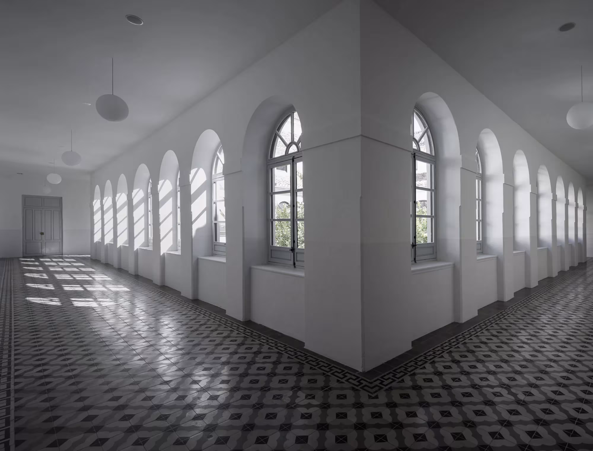Galería en esquina con ventanas de arco y suelo hidráulico en blanco y negro del Colegio San Fernando