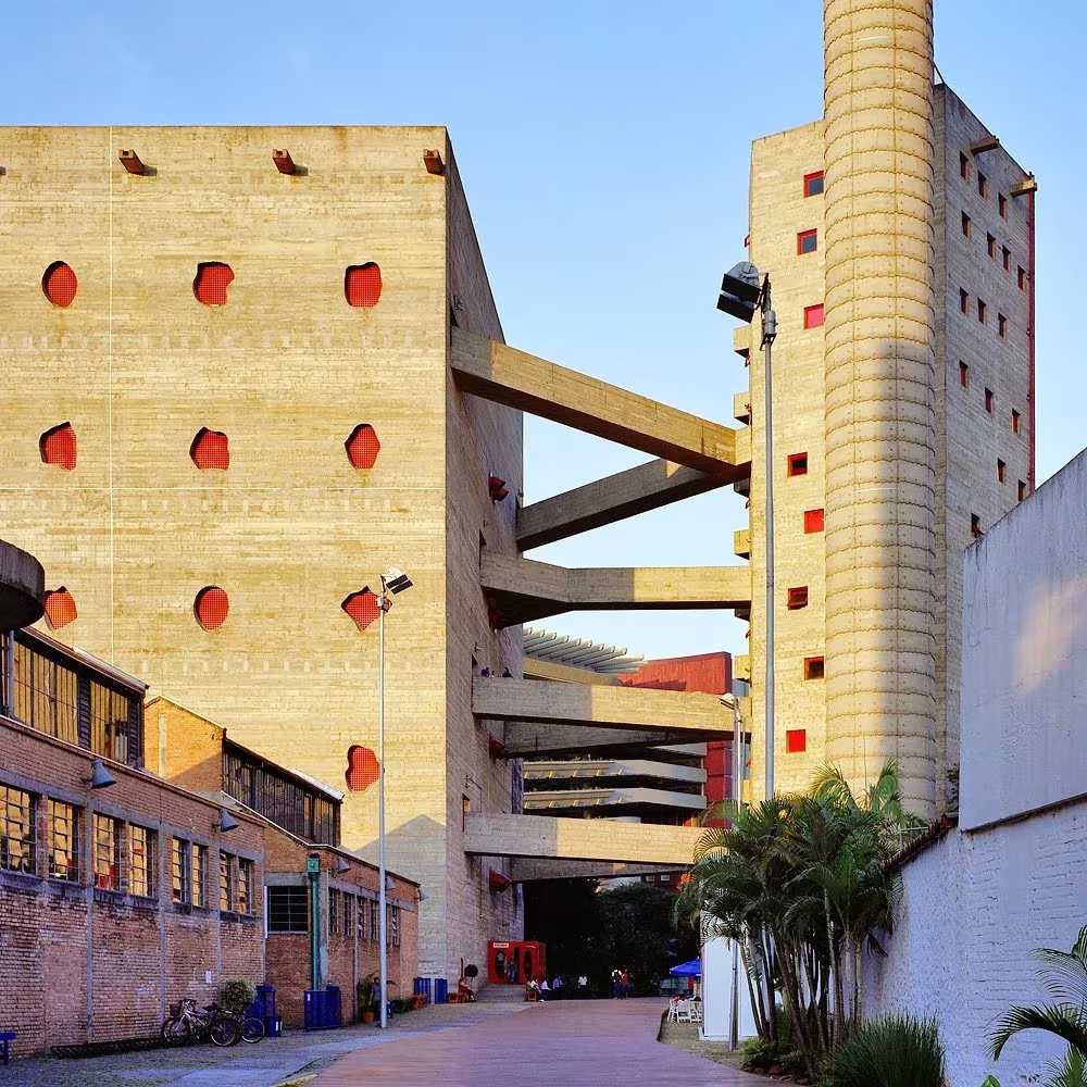 Torre de hormigón con huecos redondos rojos y pasarelas elevadas del SESC Pompéia de Lina Bo Bardi