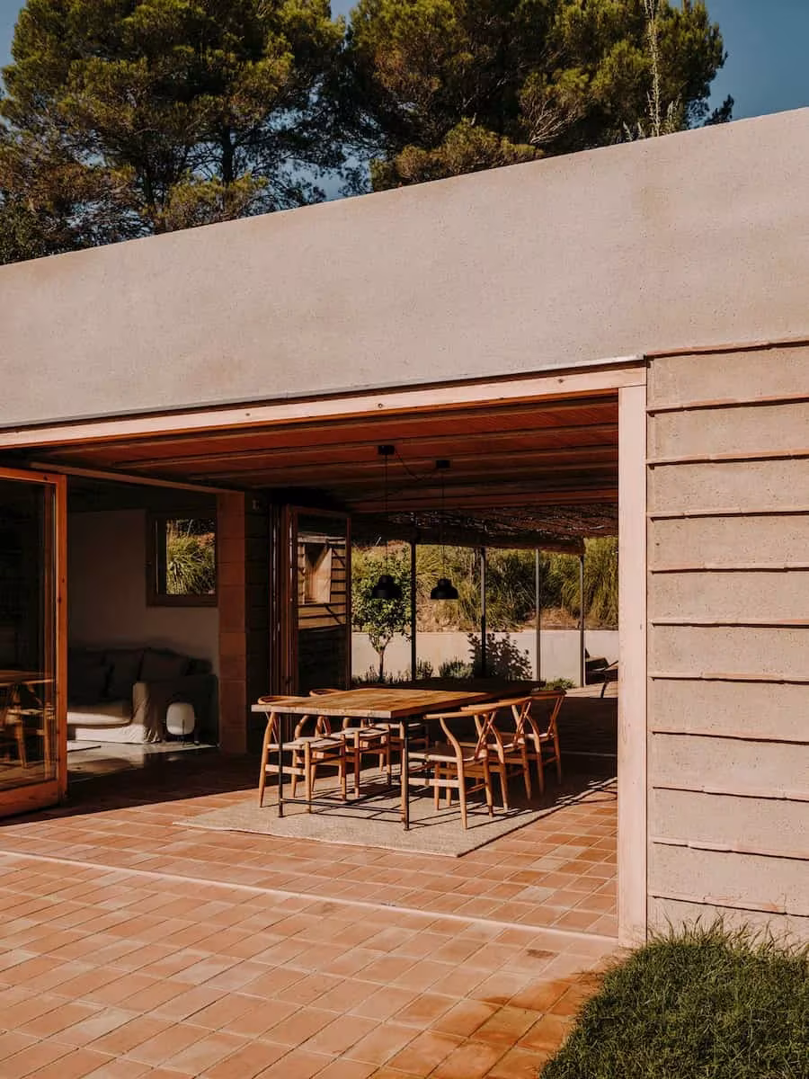 Porche de la Casa Ter con pavimento de cerámica y estancia abierta entre encinas, obra del estudio Mesura