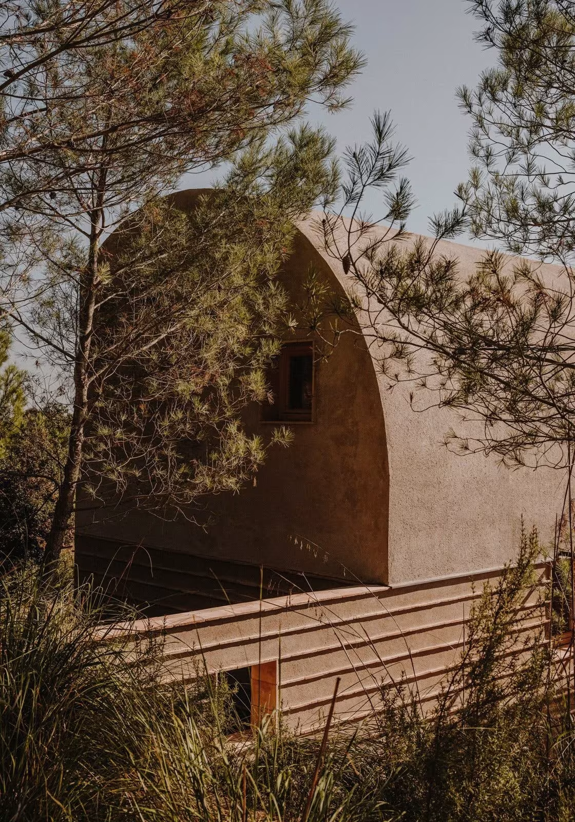 Bóveda de la Casa Ter de Mesura entre pinos, con muros de piedra de río y una pequeña ventana