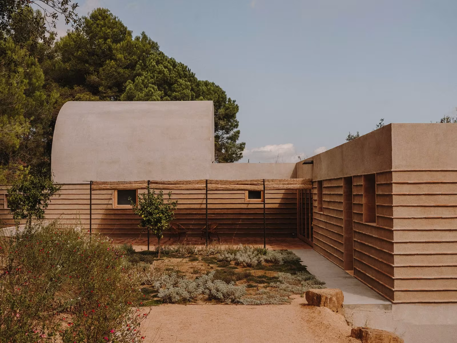 Patio de la Casa Ter con jardín seco, muros de piedra y la bóveda revocada al fondo