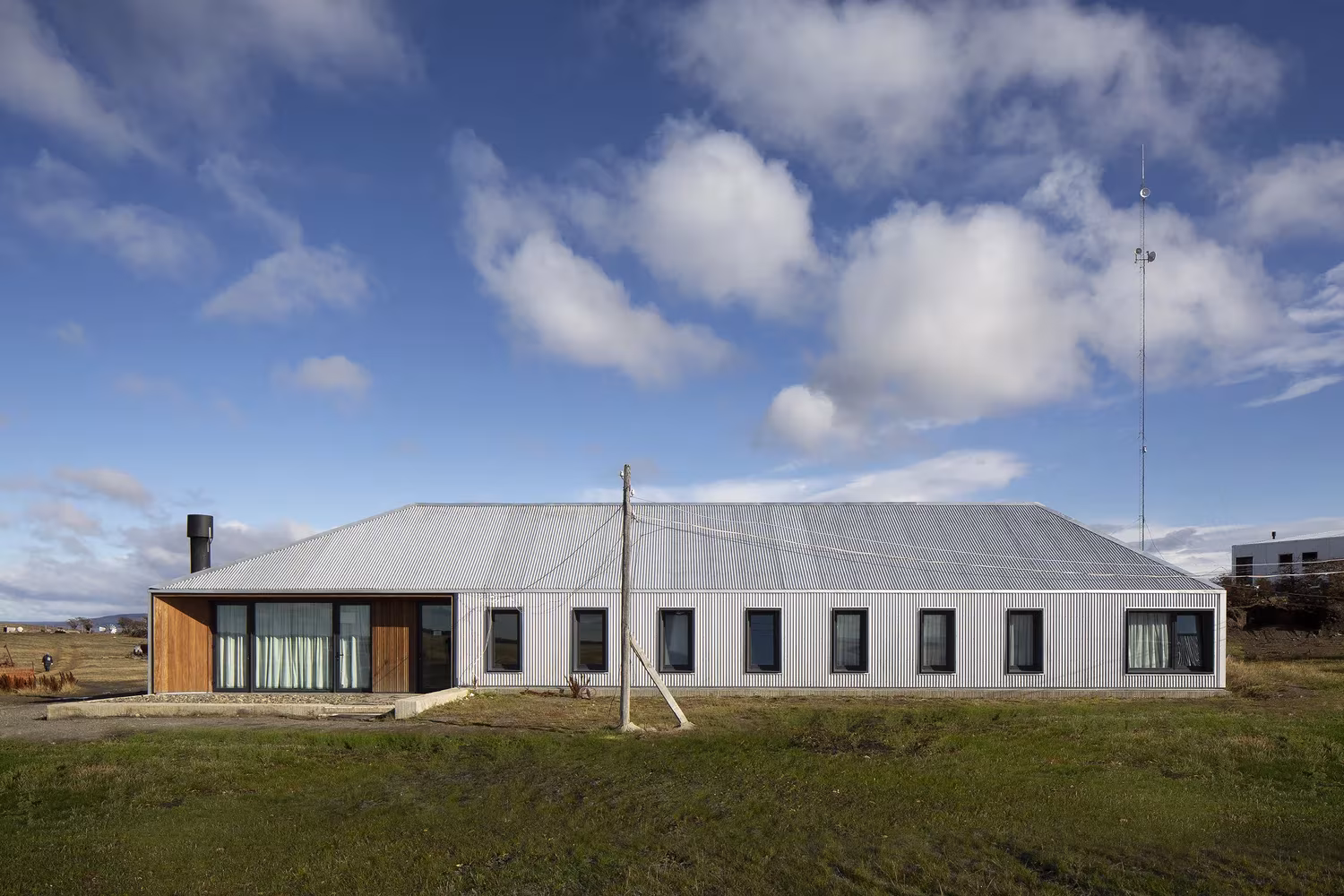 Edificio alargado de chapa blanca con ventanas y carpintería de madera en Morro Chico, Patagonia
