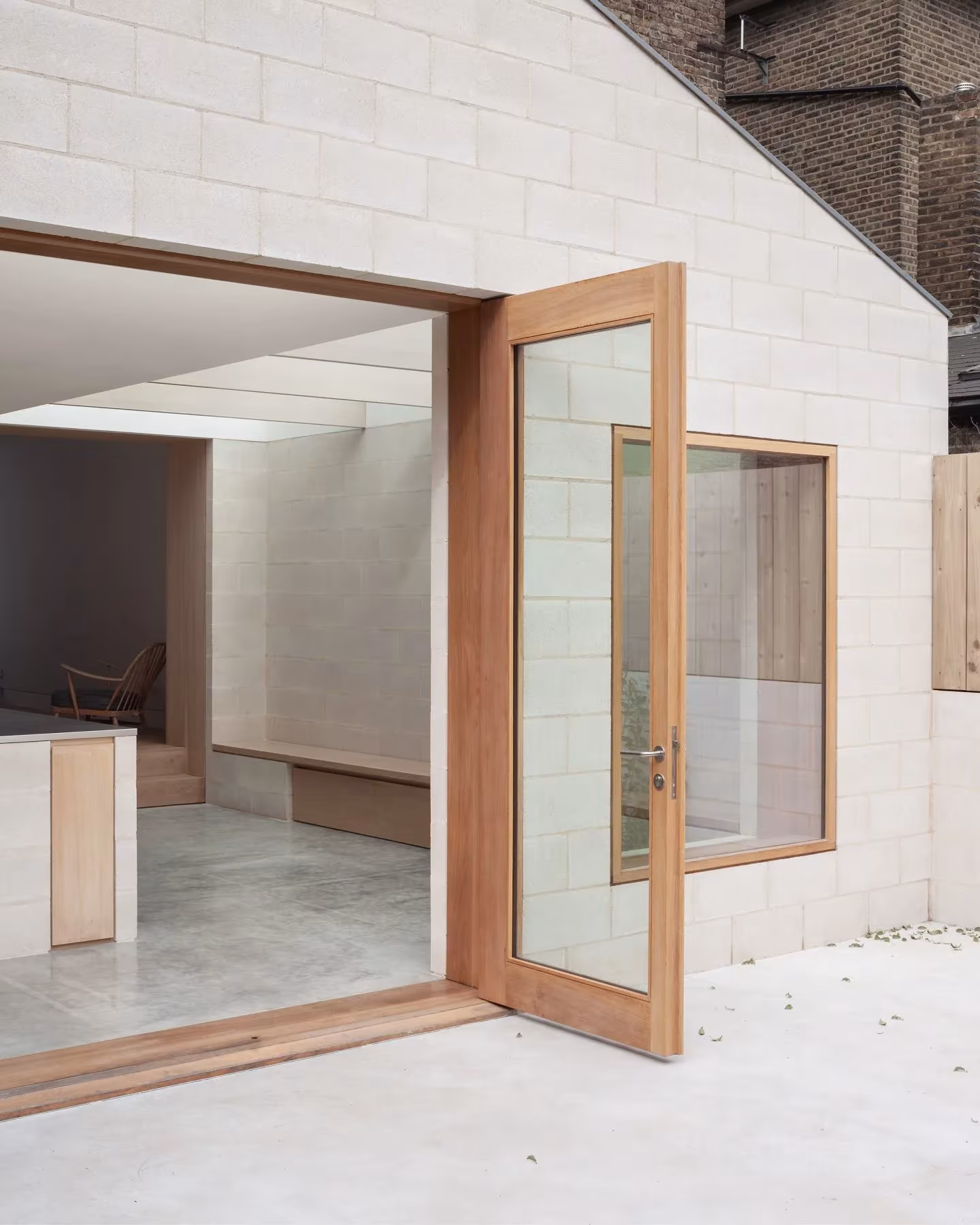 Puerta de vidrio y madera abierta al patio en la ampliación de hormigón de una casa victoriana en Peckham