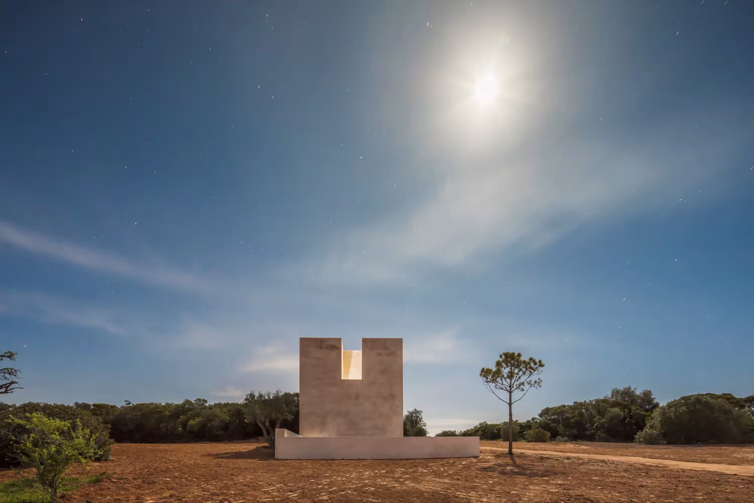 Capela do Monte de Siza bajo la luna llena, monolito aislado en el campo del Algarve