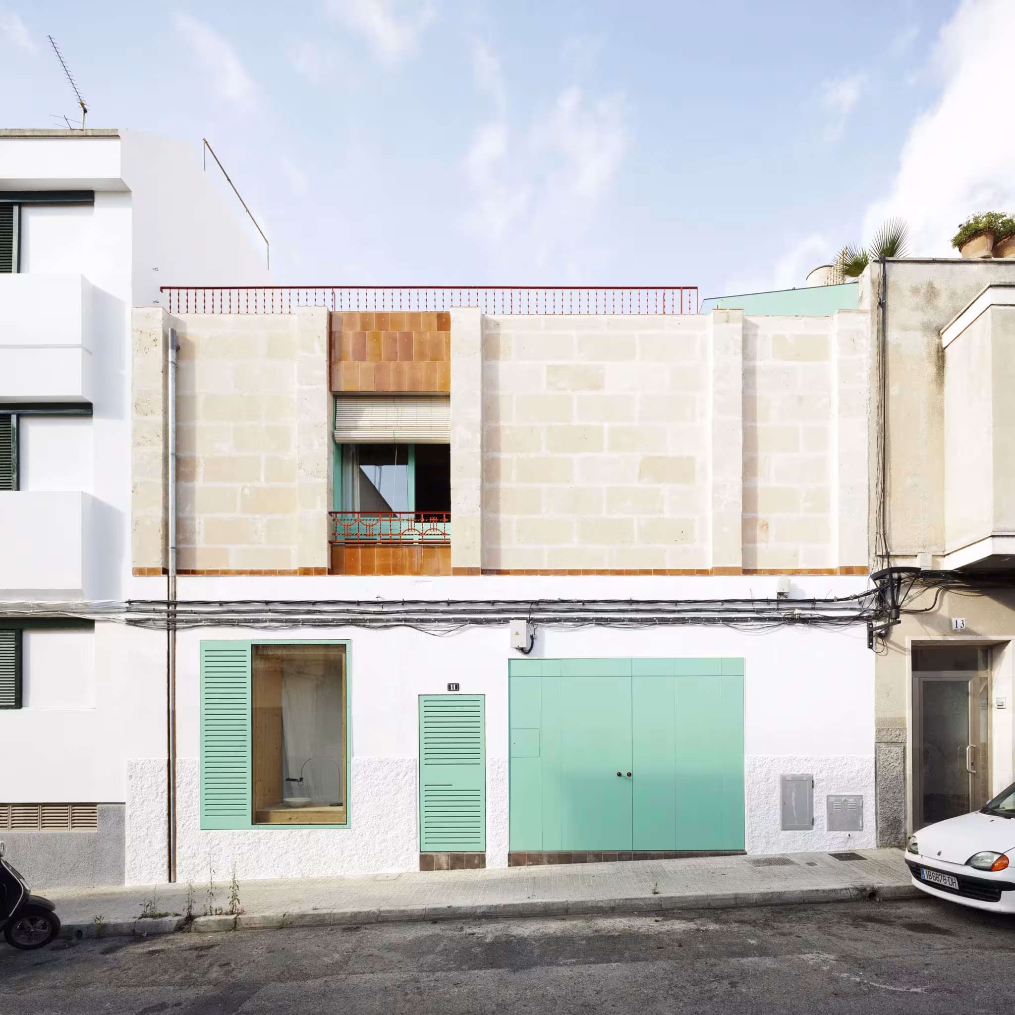 Fachada a la calle de la Plywood House de Feina con persianas y puerta verdes en Palma
