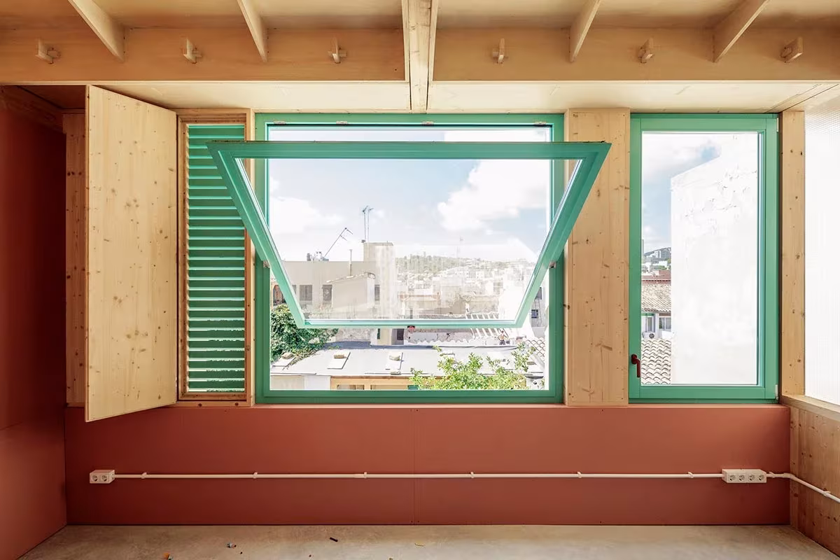 Ventana verde abatible con contraventanas de madera y vistas a los tejados de Palma, Plywood House
