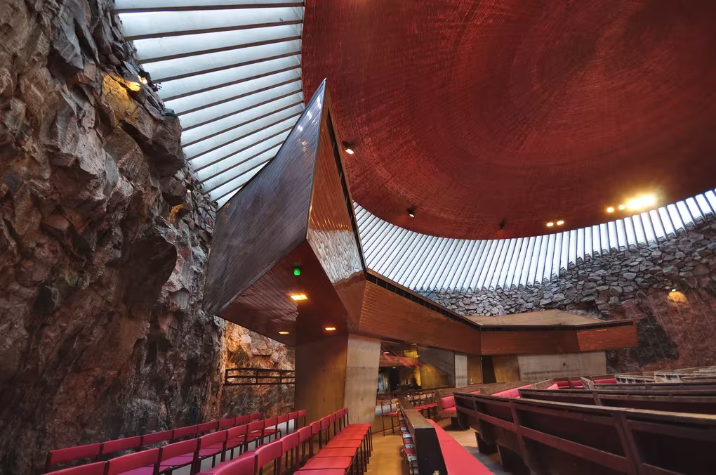 Nave de Temppeliaukio con muro de roca, cúpula de cobre y bancos rojos, de los hermanos Suomalainen