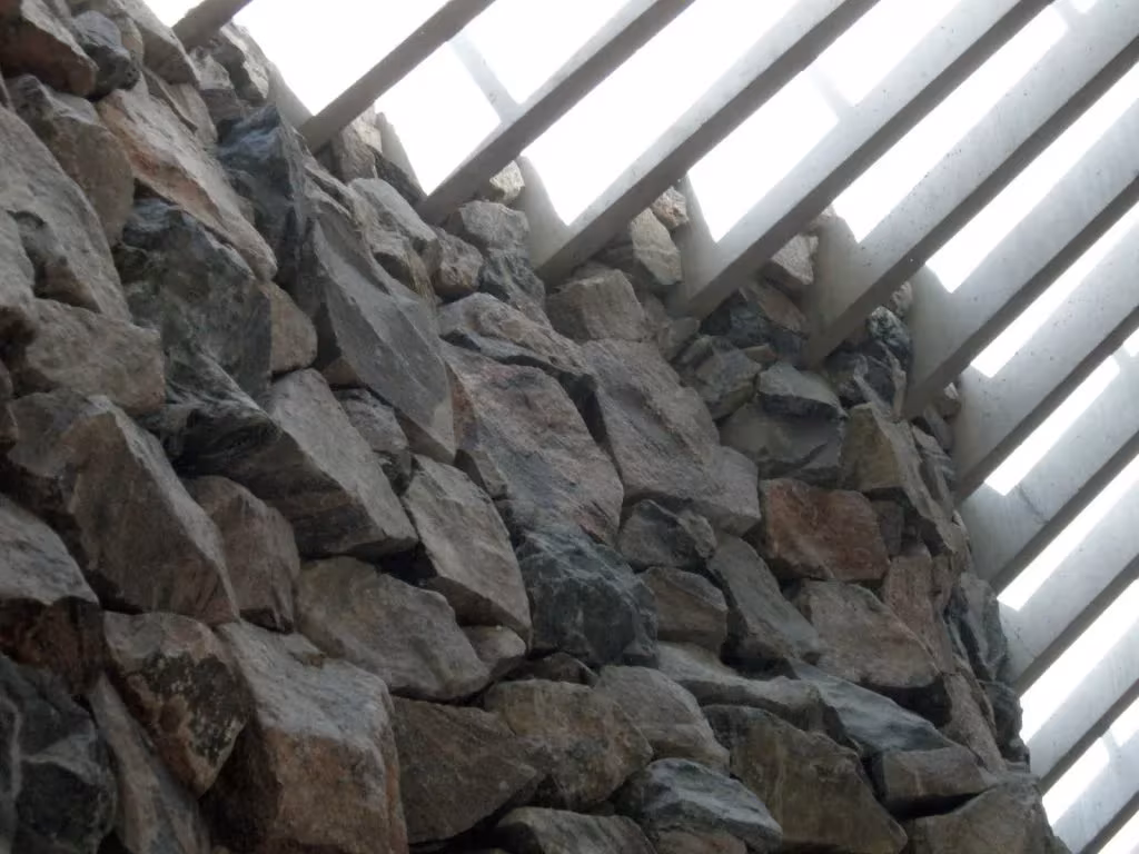 Muro de bloques de roca bruta y lamas de la claraboya perimetral en Temppeliaukio, Helsinki