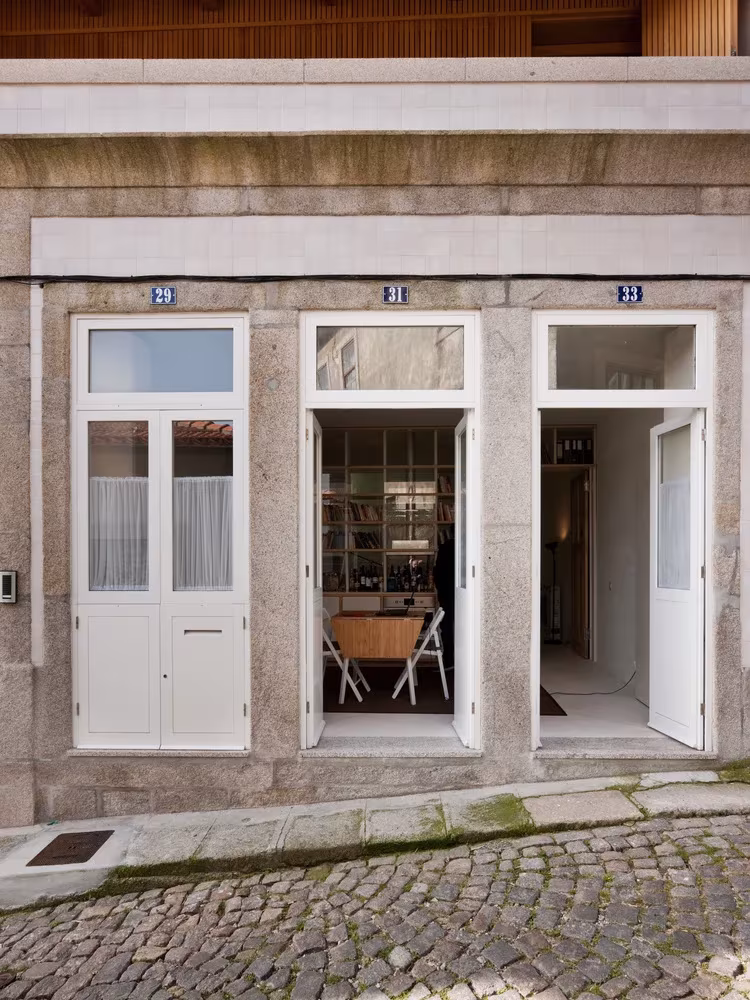 Fachada de la Casa de João con tres puertas de madera blanca abiertas al interior, en Oporto