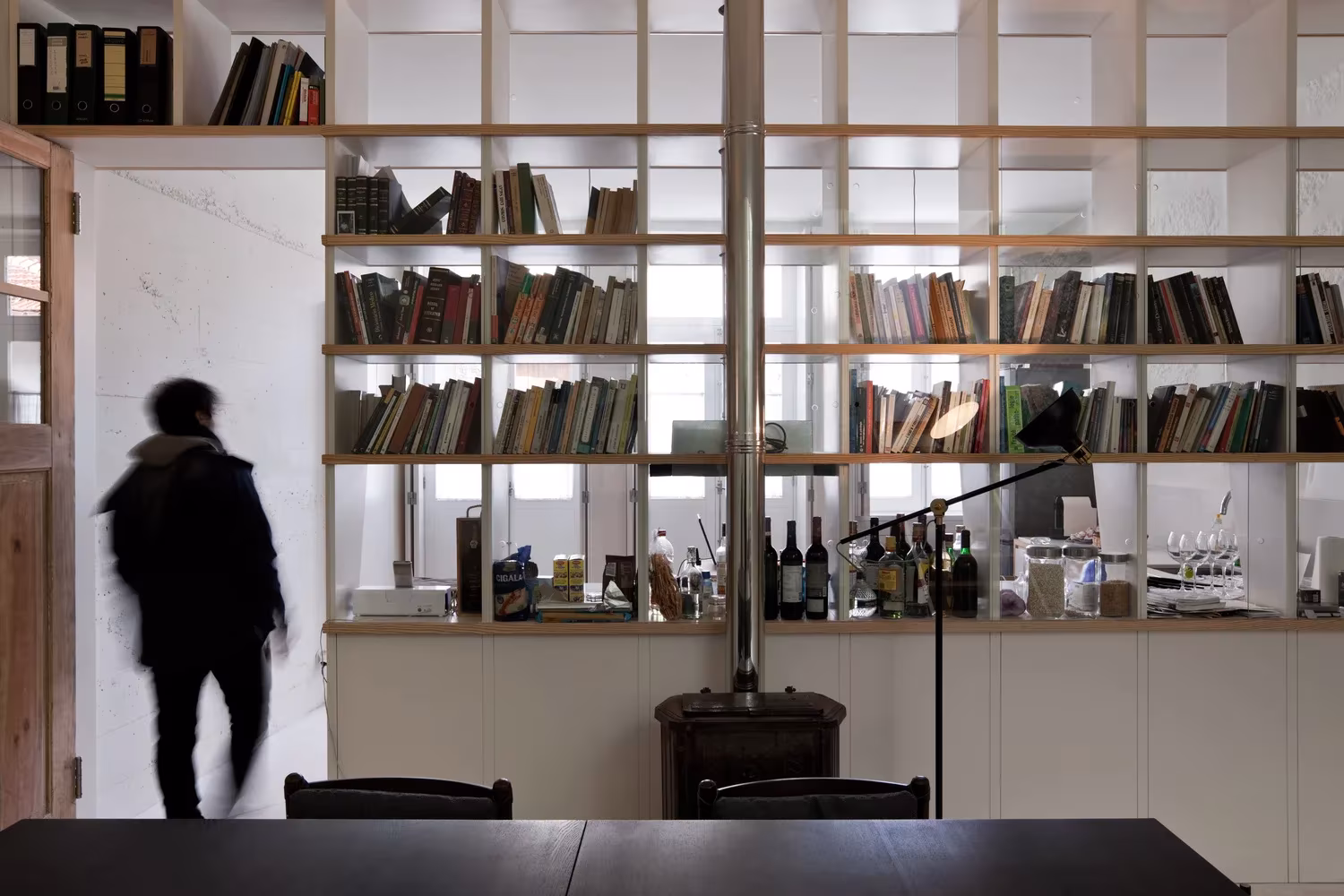 Estantería de madera con libros y mesa negra en el interior de la Casa de João, Oporto