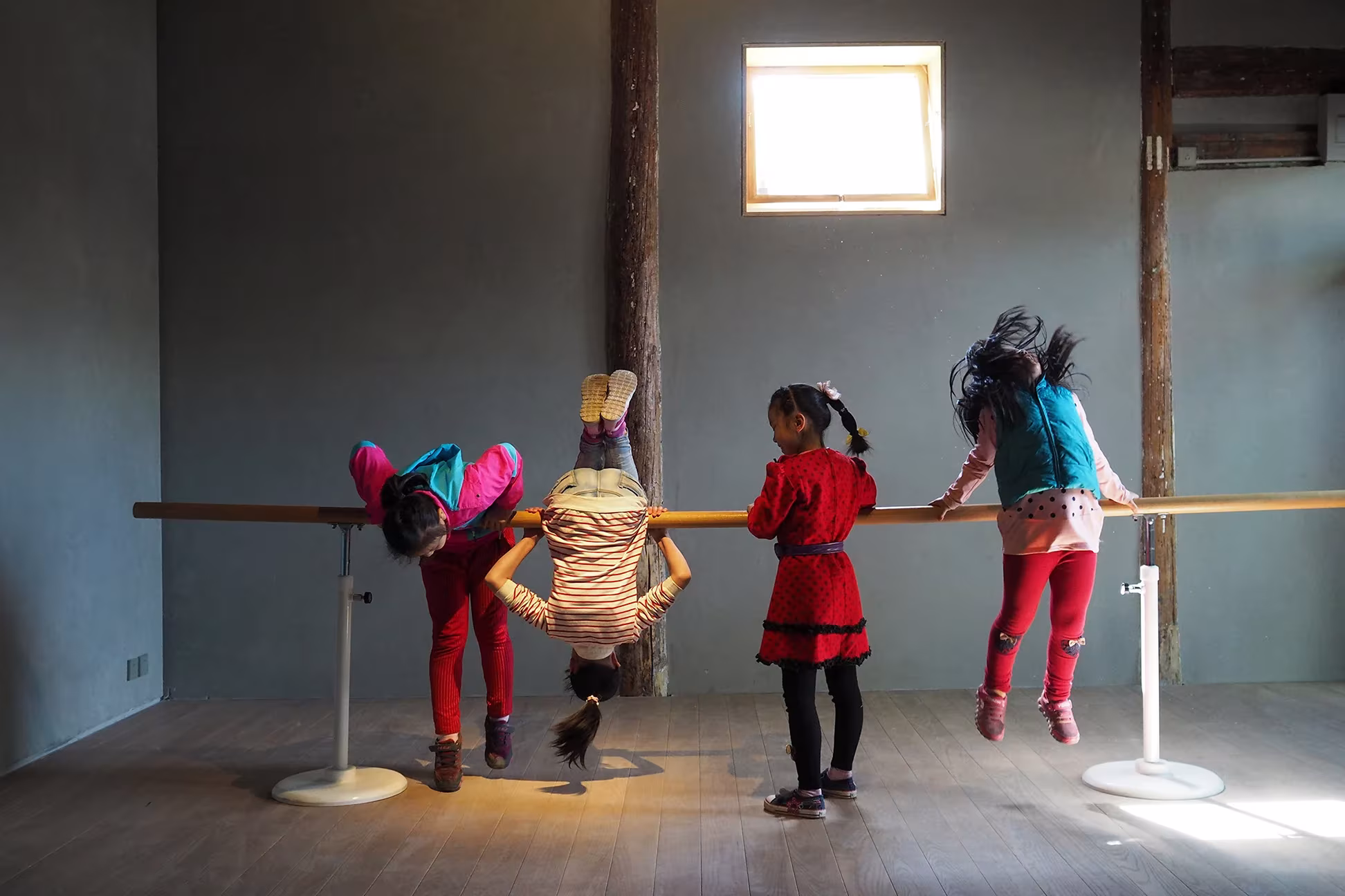 Niños jugando con una barra de madera bajo una pequeña ventana en un aula del hutong de Pekín
