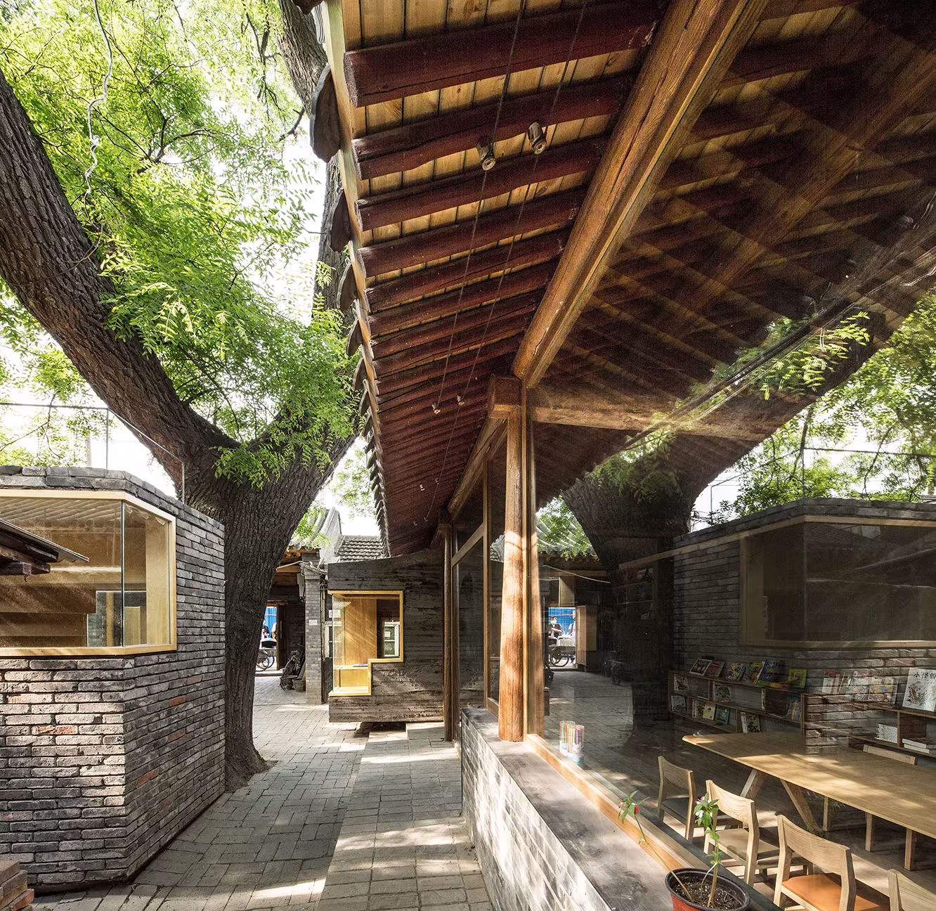 Galería cubierta de madera junto a la biblioteca infantil bajo los árboles del hutong de Pekín