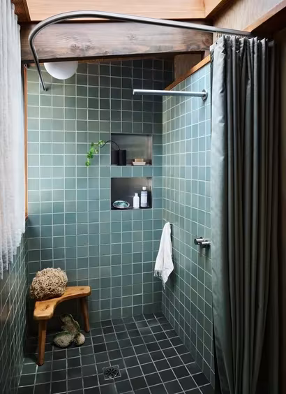 Ducha con azulejos verdes y cortina gris bajo un techo de madera en la Pilot House restaurada