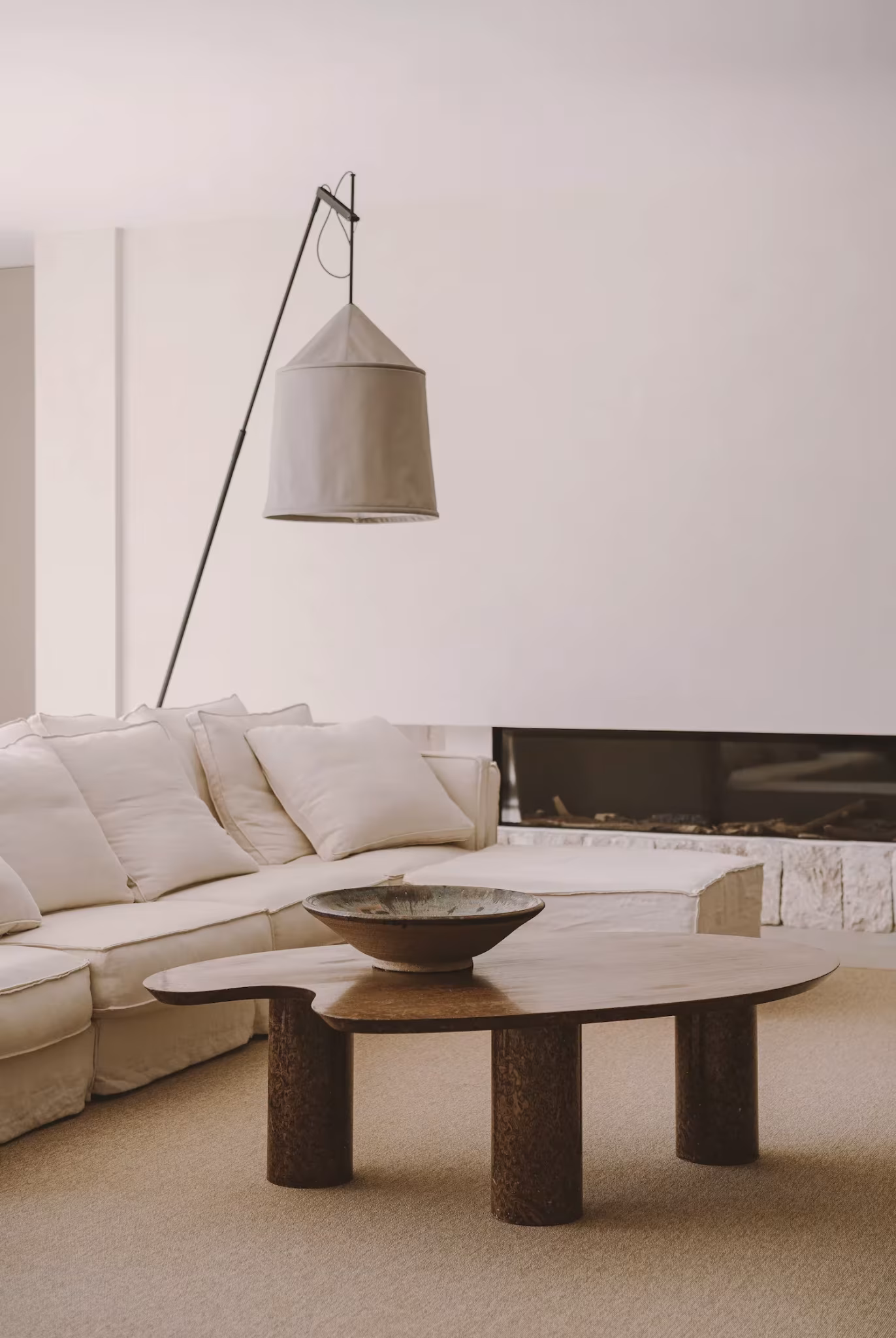 Mesa baja de madera con cuenco, sofá blanco y lámpara de pie en el salón de la PDM House, Palma