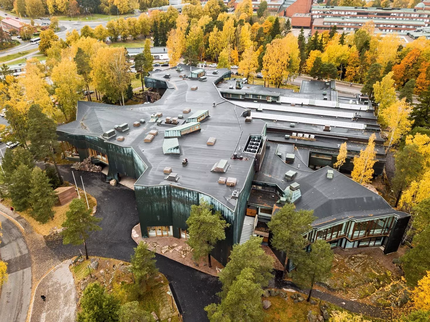 Vista aérea de Dipoli entre abedules otoñales con sus cubiertas de cobre en el campus de Aalto, Finlandia