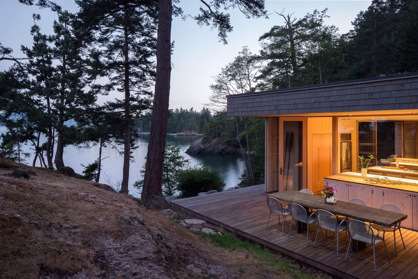 Terraza de Lone Madrone con mesa de comedor exterior junto a la cocina iluminada y una cala
