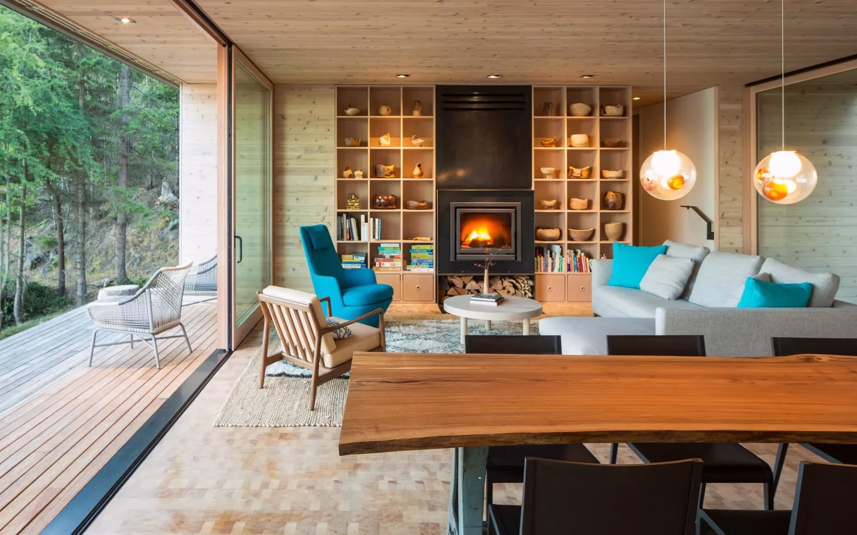 Salón de Lone Madrone con estufa de leña, librería de madera, sillones turquesa y mesa de tablón