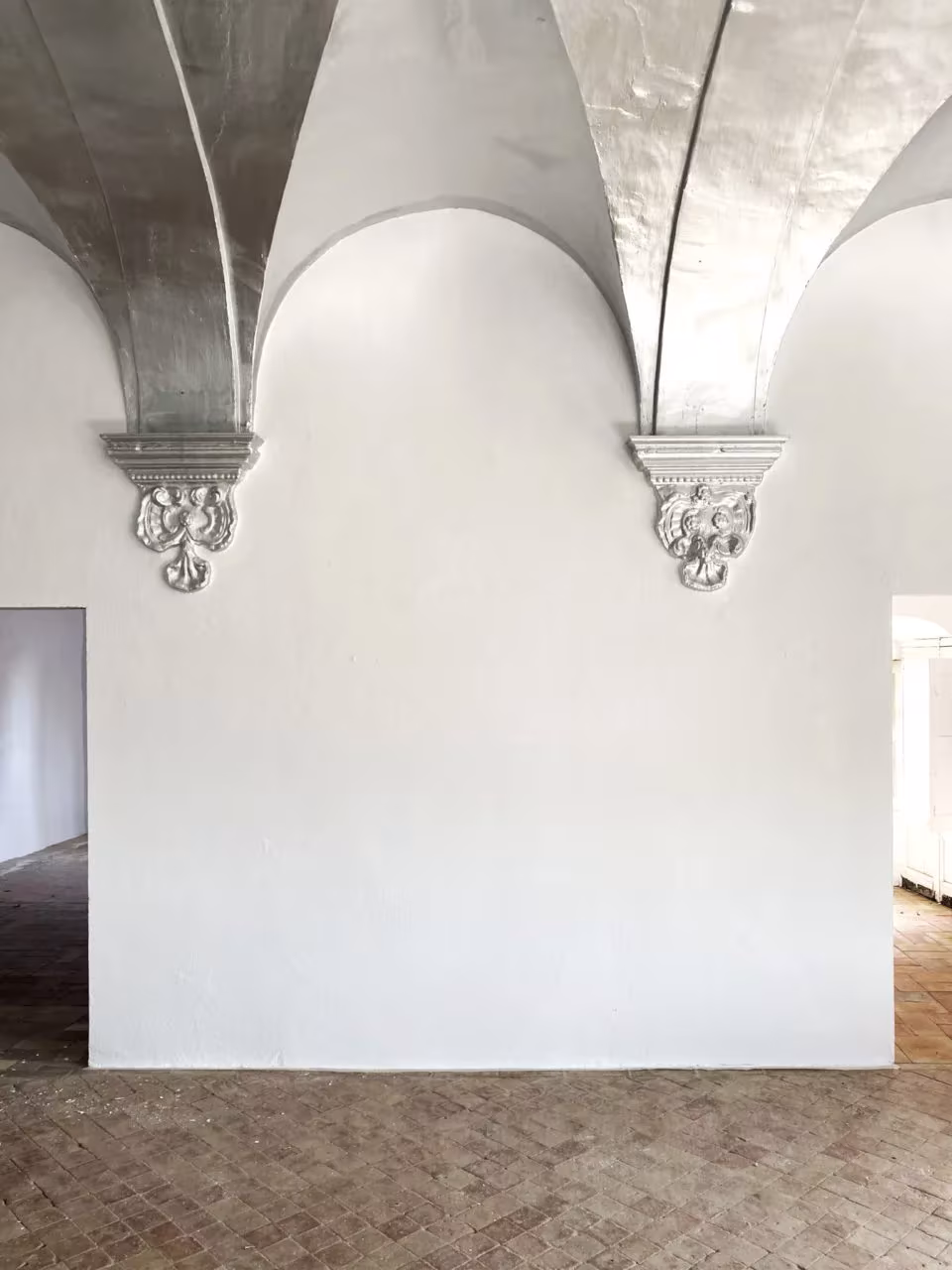 Bóvedas de crucería plateadas con ménsulas ornamentadas sobre una pared blanca en el Palau de Casavells