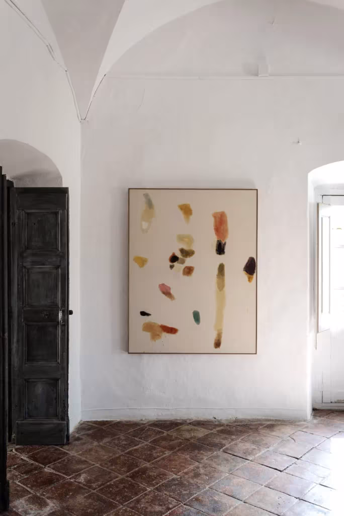 Sala encalada con una pintura abstracta y suelo de ladrillo en espiga en el Palau de Casavells