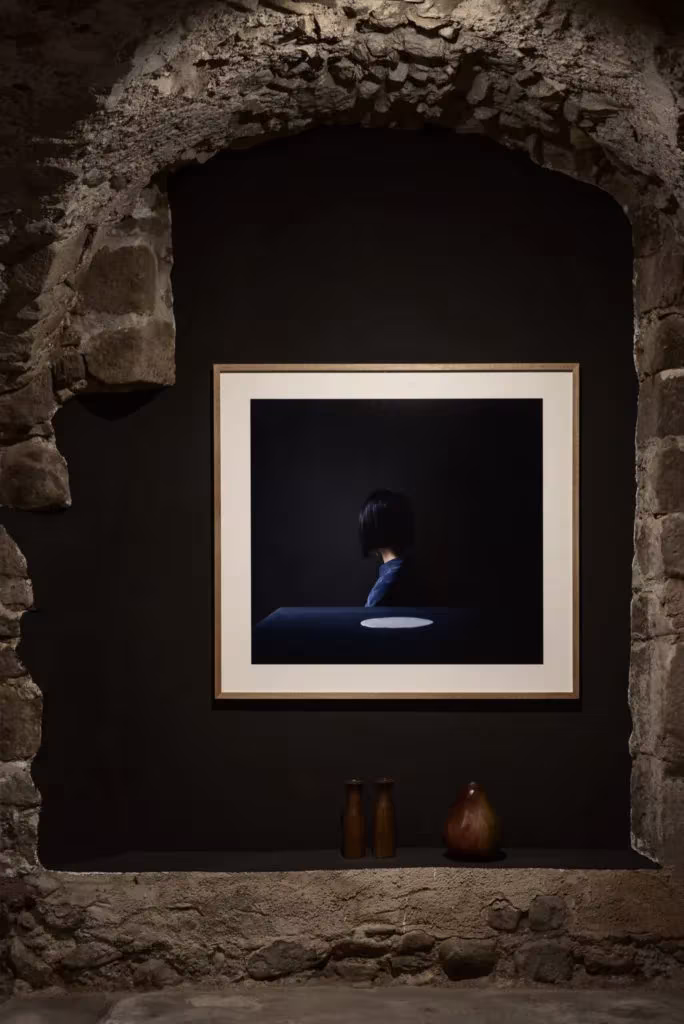 Hornacina de piedra rústica con una fotografía enmarcada sobre fondo negro en el Palau de Casavells