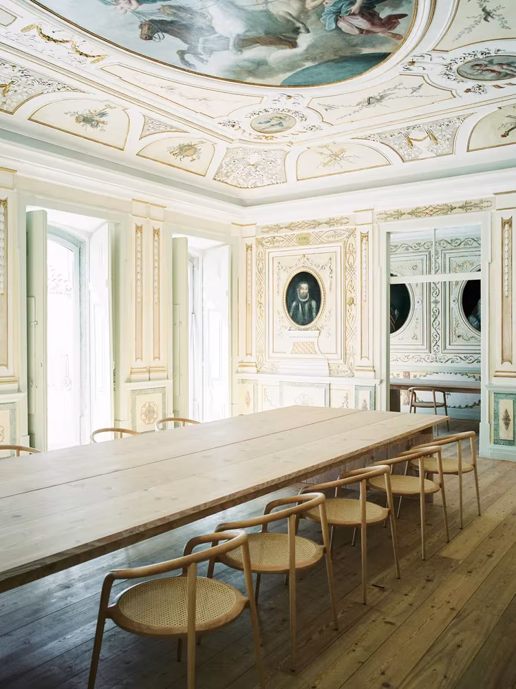 Larga mesa de madera y sillas bajo el techo pintado del Atelier Cecílio de Sousa, estudio de Aires Mateus