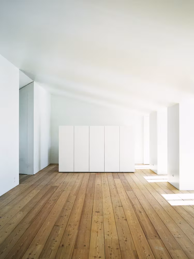 Espacio blanco con armarios empotrados y suelo de tablas de madera en el Atelier Cecílio de Sousa, Lisboa