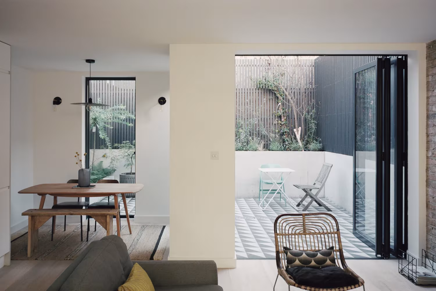 Comedor con mesa de madera y plegable de vidrio abierta a un patio de baldosa hidráulica en Corner House