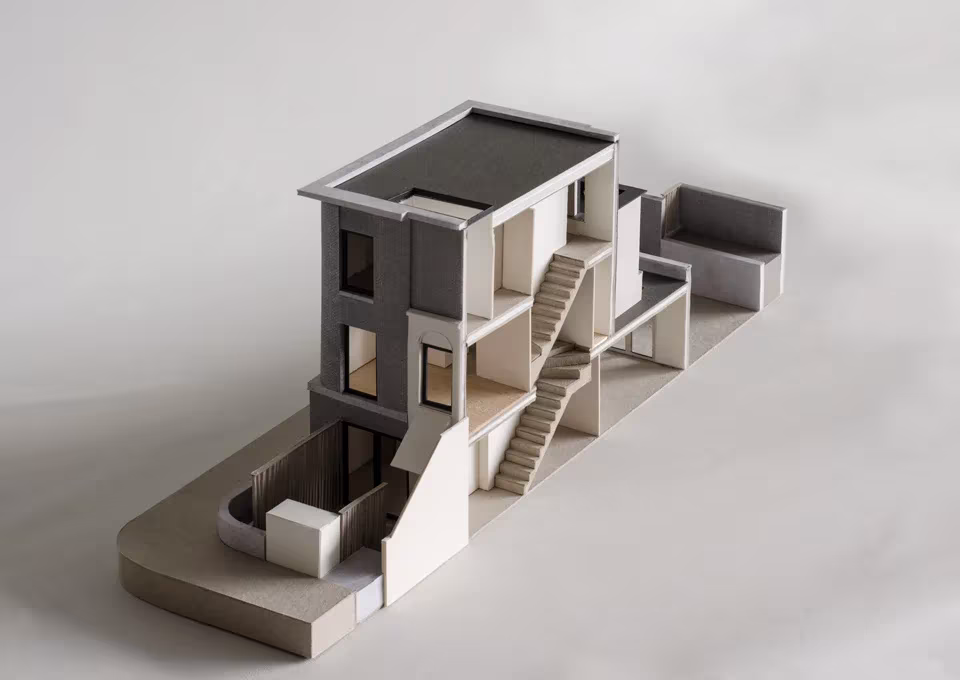 Maqueta seccionada de Corner House de 31/44 Architects con escalera exterior y patio inferior