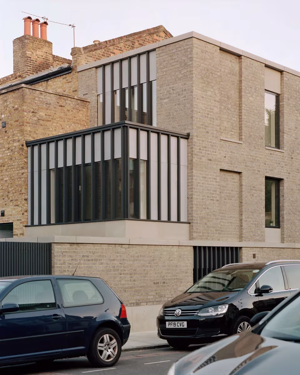 Corner House de 31/44 Architects con volumen acristalado de carpintería metálica sobre zócalo de ladrillo, Londres