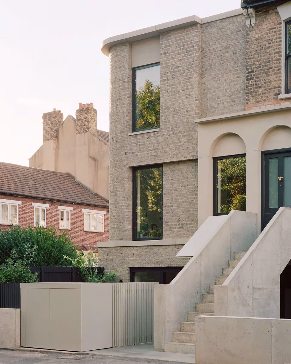 Fachada de ladrillo con arcos y escalera exterior de hormigón de Corner House en Peckham, de 31/44 Architects