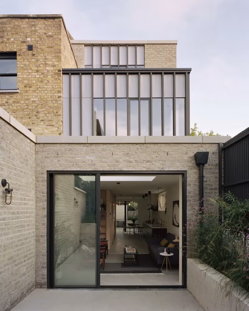 Trasera de Corner House con puerta corredera de vidrio abierta al interior de la vivienda, Peckham, Londres