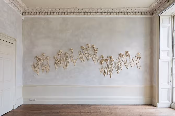 Hilera de flores de gres blanco sobre una pared de sala con molduras, de Kaori Tatebayashi en The Walled Garden