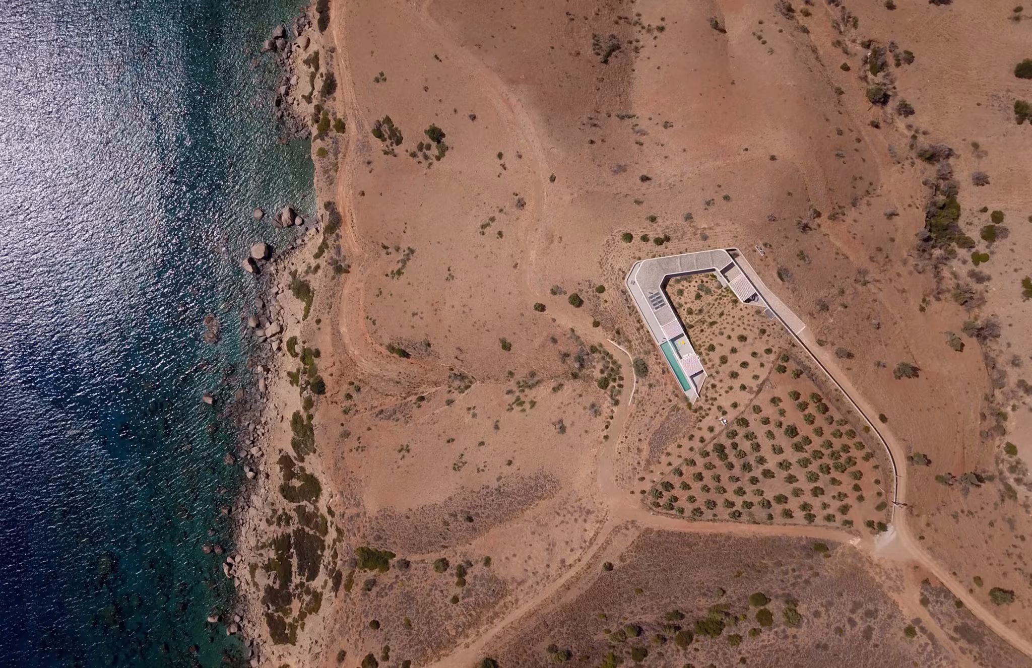 Planta anular de la Ring House de DECA Architecture vista desde el aire junto al mar y los olivos de Creta