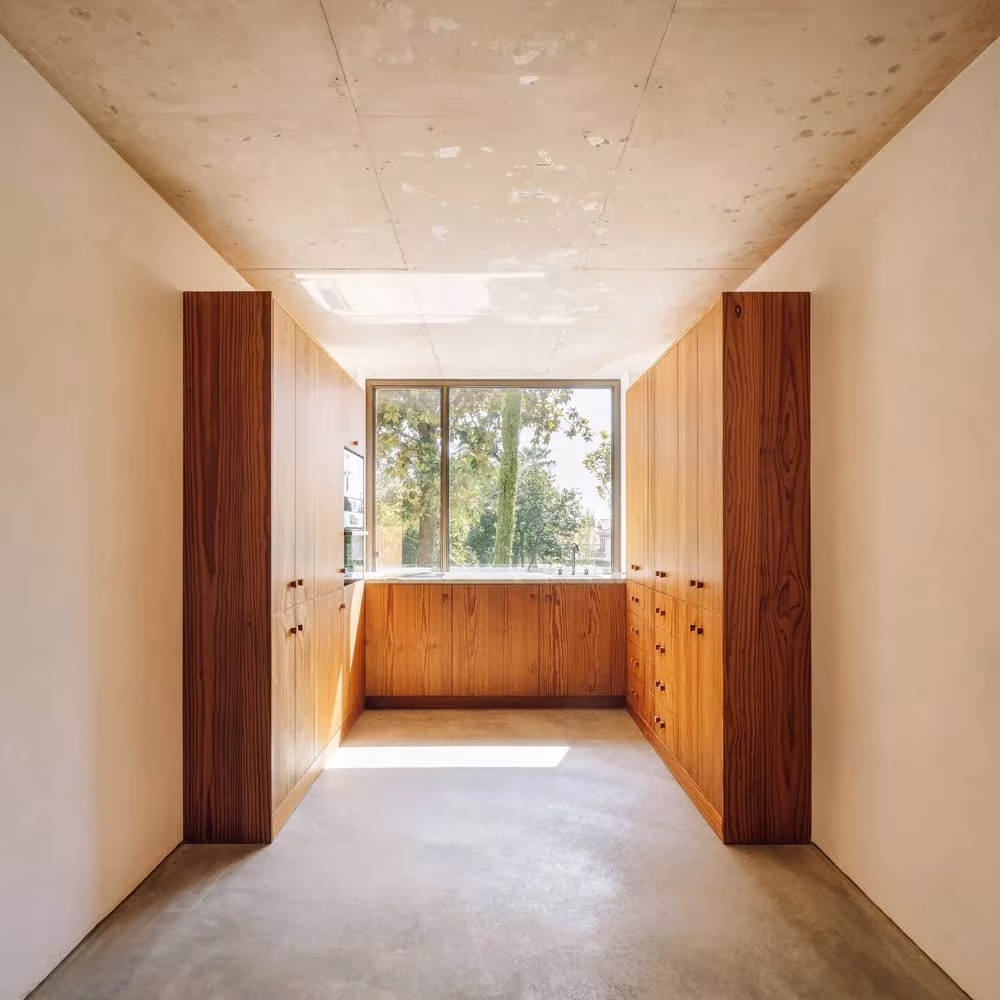 Vestidor con armarios de madera a ambos lados y ventana al jardín, con suelo continuo, en la Casa 2 de Ricardo Bak Gordon