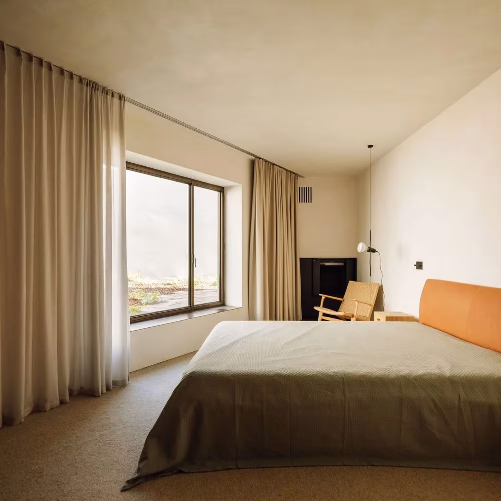 Dormitorio con cortinas de lino, ventana al jardín y cabecero de cuero en la Casa 2 de Oporto