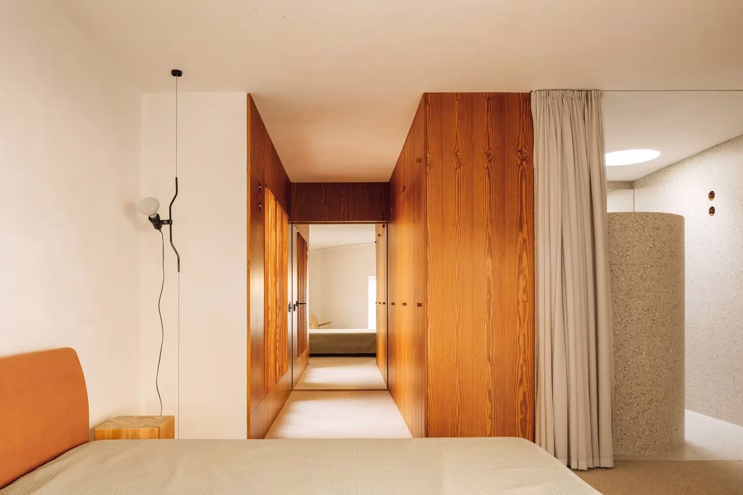 Dormitorio en eje con vestidor de madera y baño tras una cortina en la Casa 2 de Ricardo Bak Gordon, Oporto