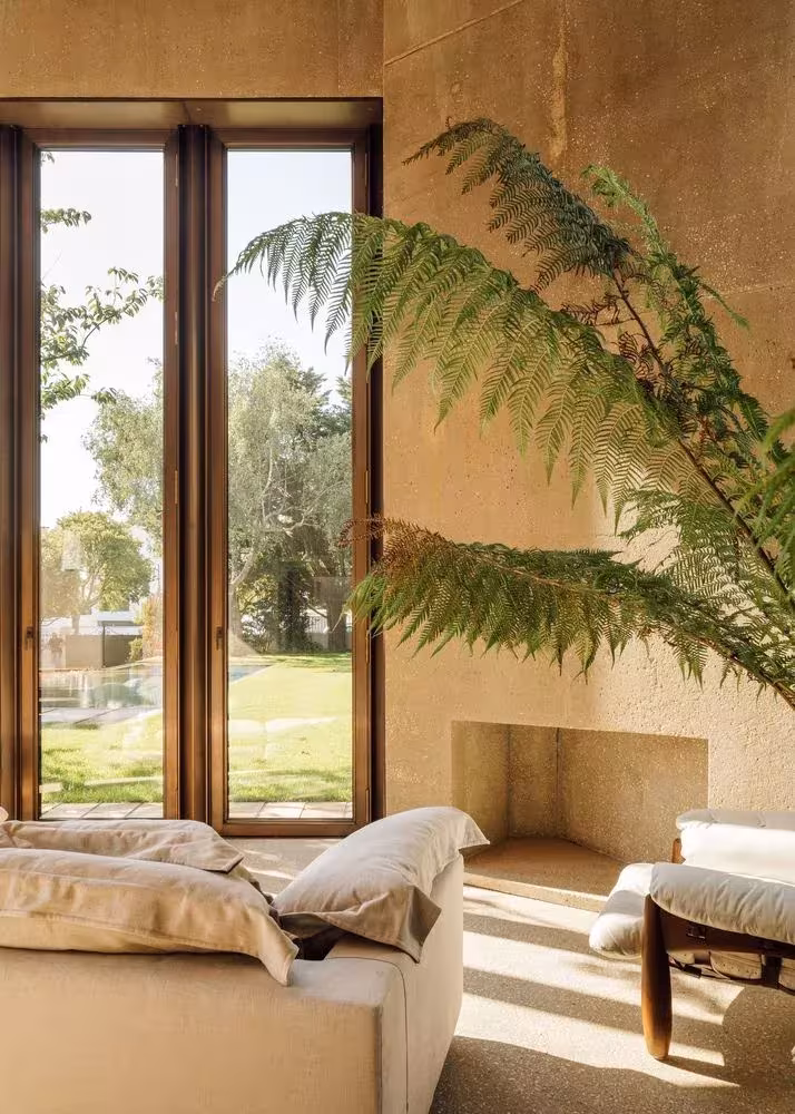 Salón con ventanal vertical de madera, chimenea y helecho abierto al jardín en la Casa 2 de Ricardo Bak Gordon