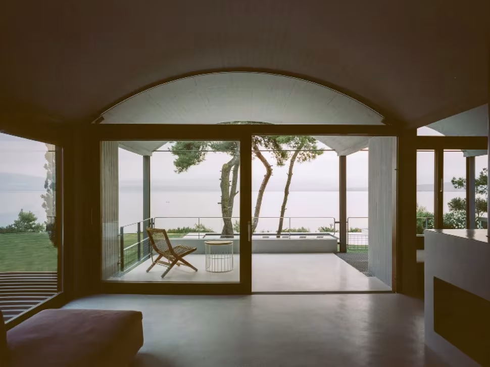 Arco de madera enmarcando una terraza con el mar y los pinos de Eubea al fondo, en St. Minas House