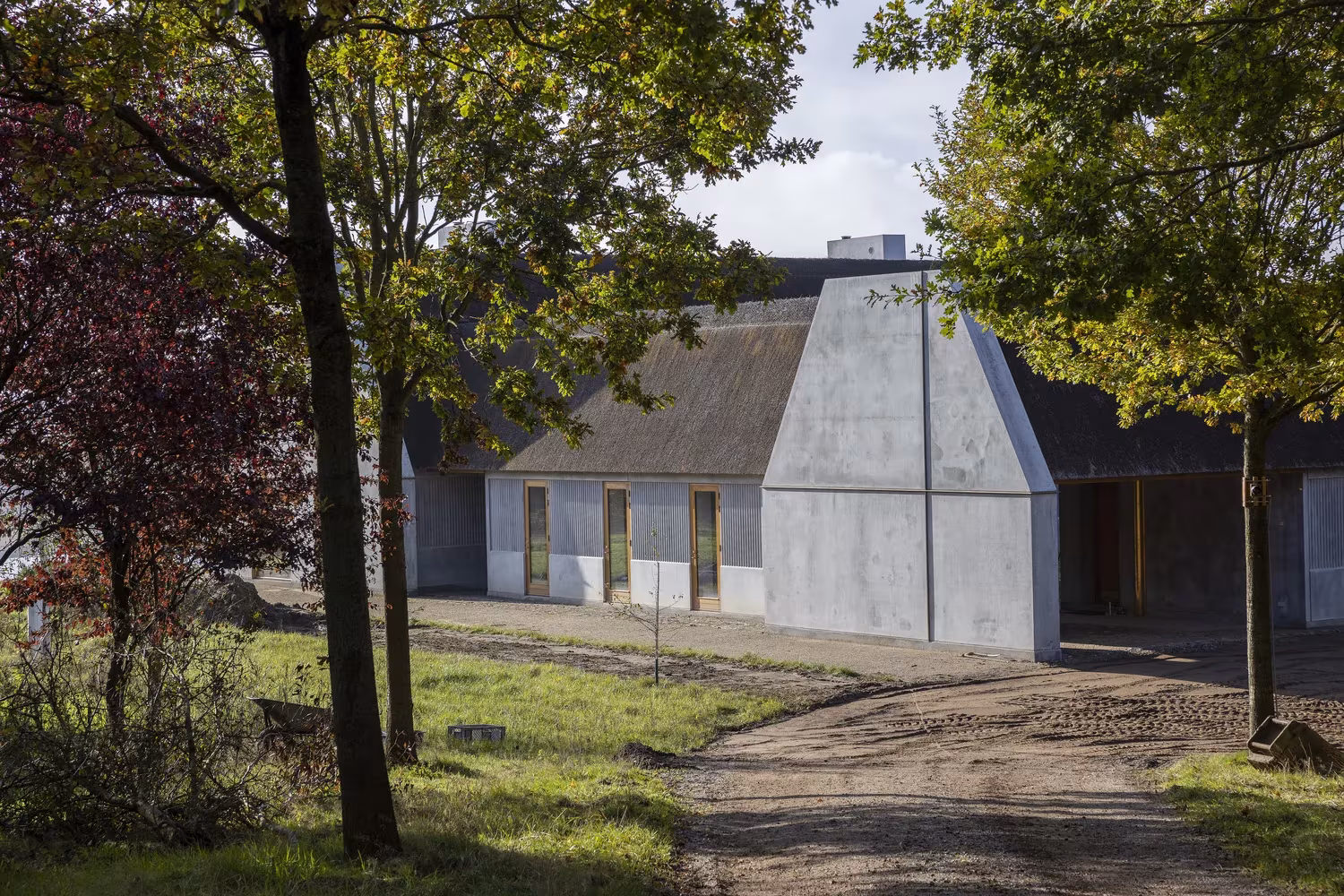 Åstrup Have de NORRØN, granja de cubierta de paja con un testero de hormigón entre los árboles