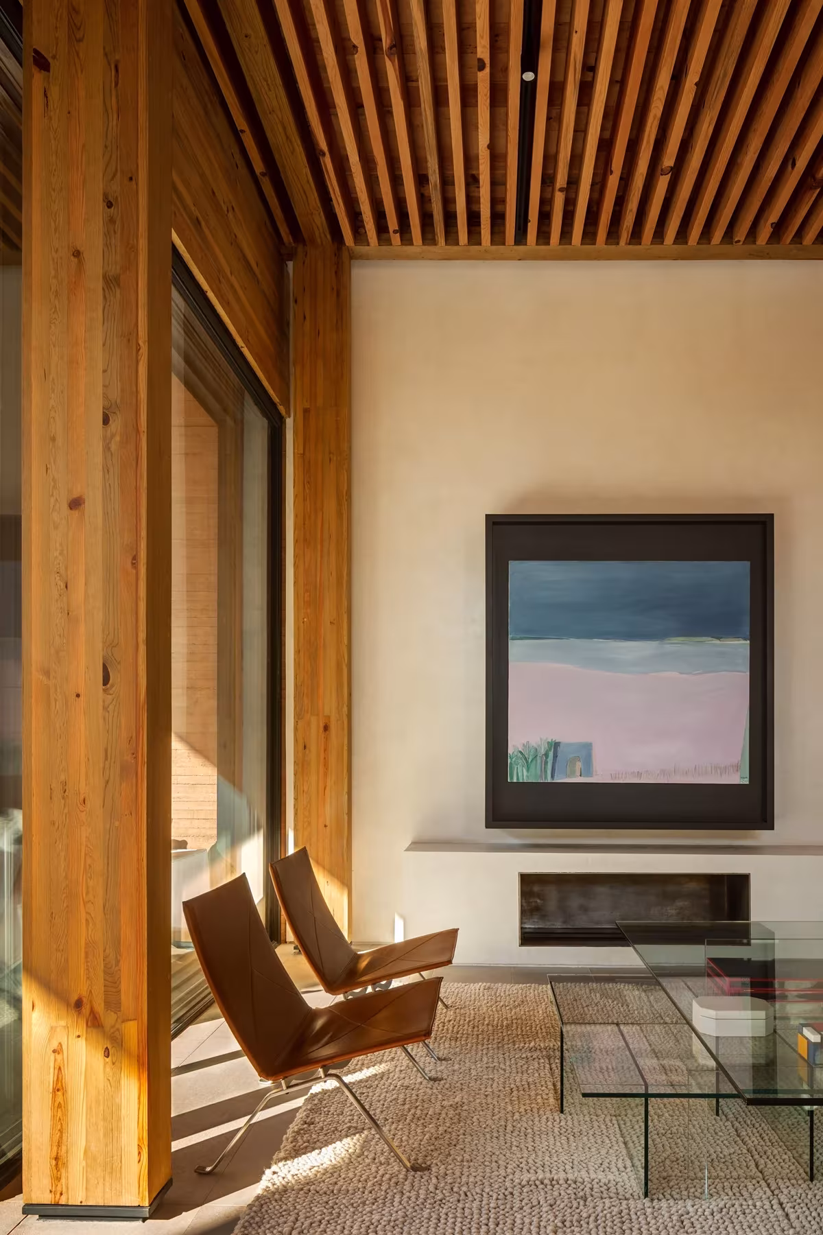 Salón de la casa Monte Tauro con pilares de madera, techo de listones, chimenea y butacas de cuero