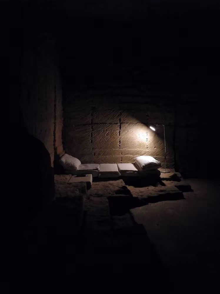 Rincón de descanso a media luz entre muros tallados en piedra en el interior de Ca'n Terra