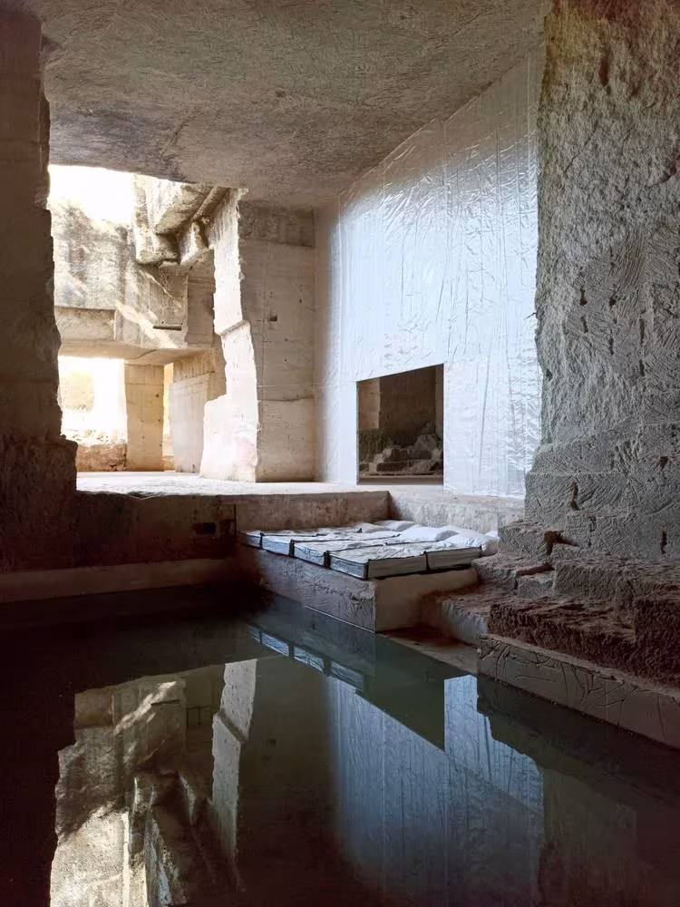 Estanque de agua en una estancia excavada de Ca'n Terra, con reflejo de los muros de piedra de la cantera