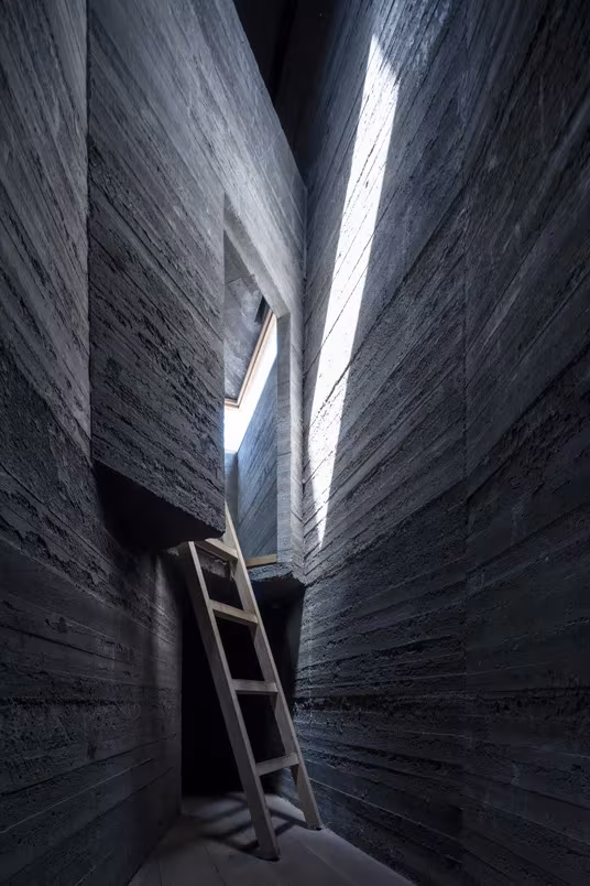Hueco vertical de hormigón encofrado con escalera de mano y luz cenital en Micro Hutong, de ZAO/standardarchitecture