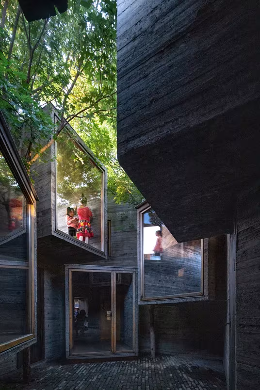 Cajas acristaladas de hormigón encofrado que se asoman al patio de Micro Hutong, entre vegetación
