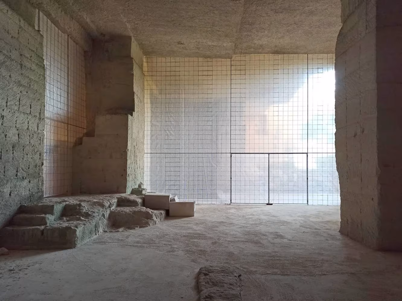 Sala excavada en la cantera de Ca'n Terra con cerramiento de malla de vidrio y luz tamizada, de Ensamble Studio