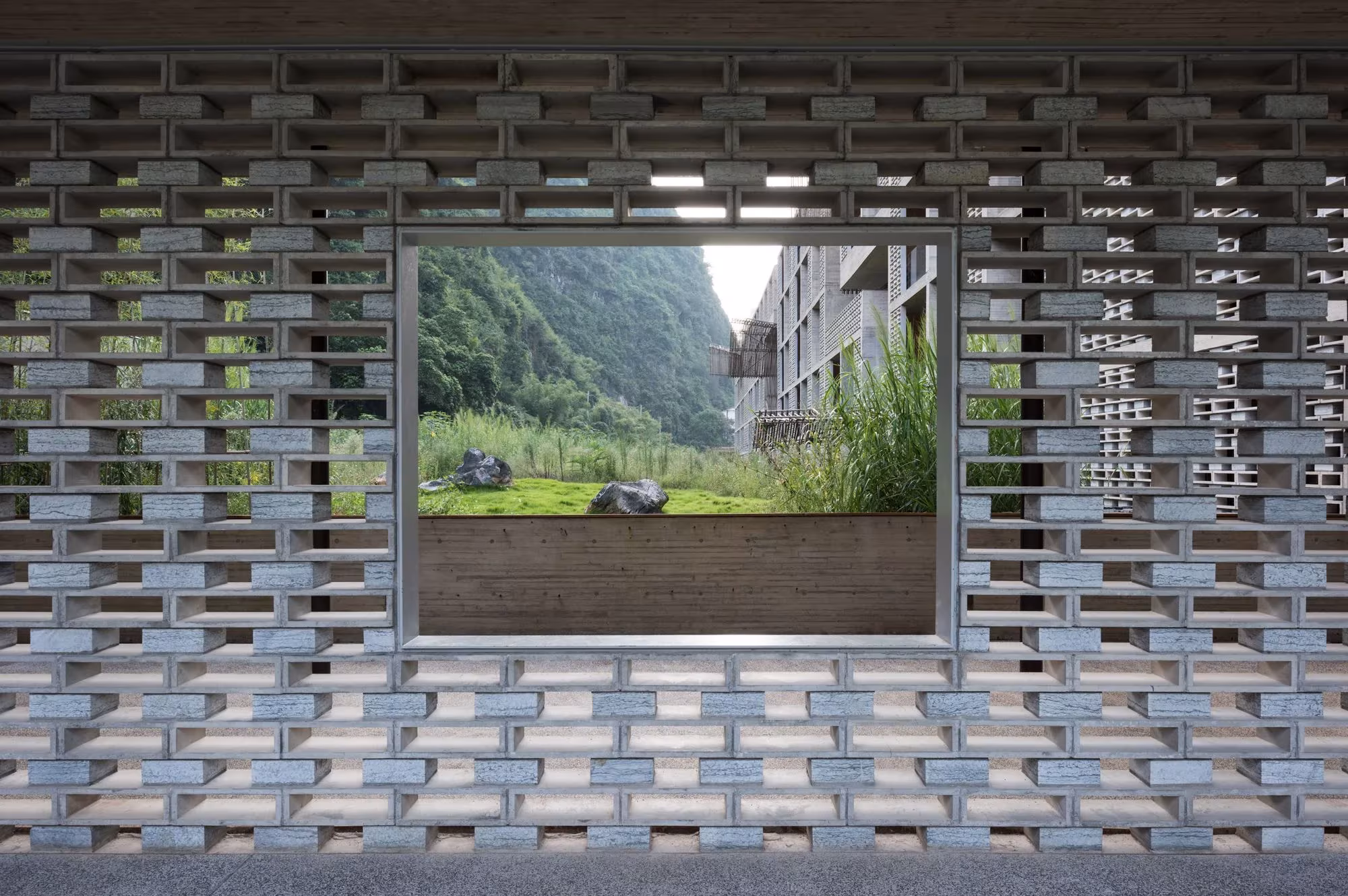 Celosía de bloques de hormigón enmarcando un patio con vegetación en el Hotel Alila Yangshuo