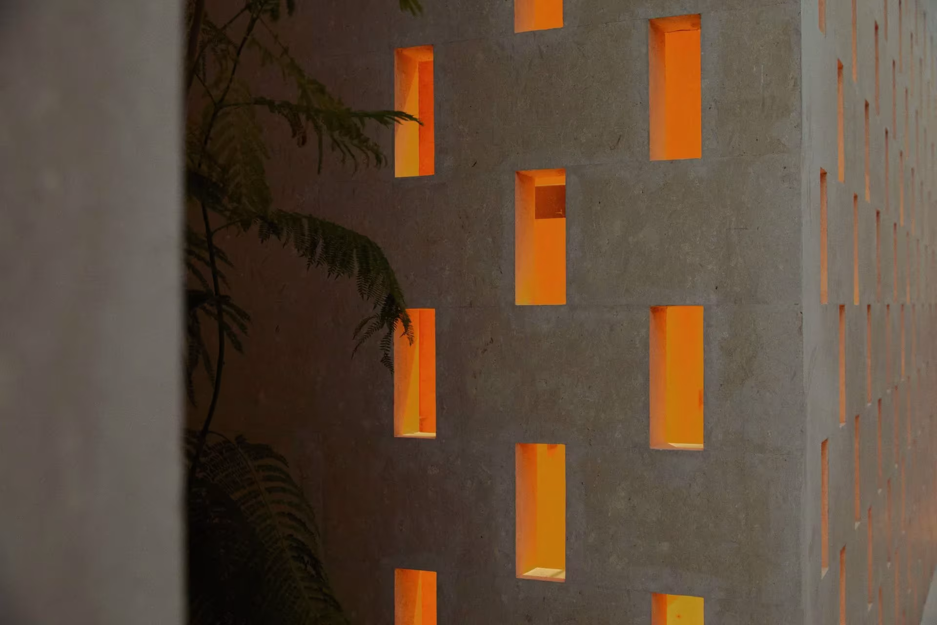 Celosía de piedra con huecos iluminados en tono naranja en Villa AM de Mesura, en Jeddah