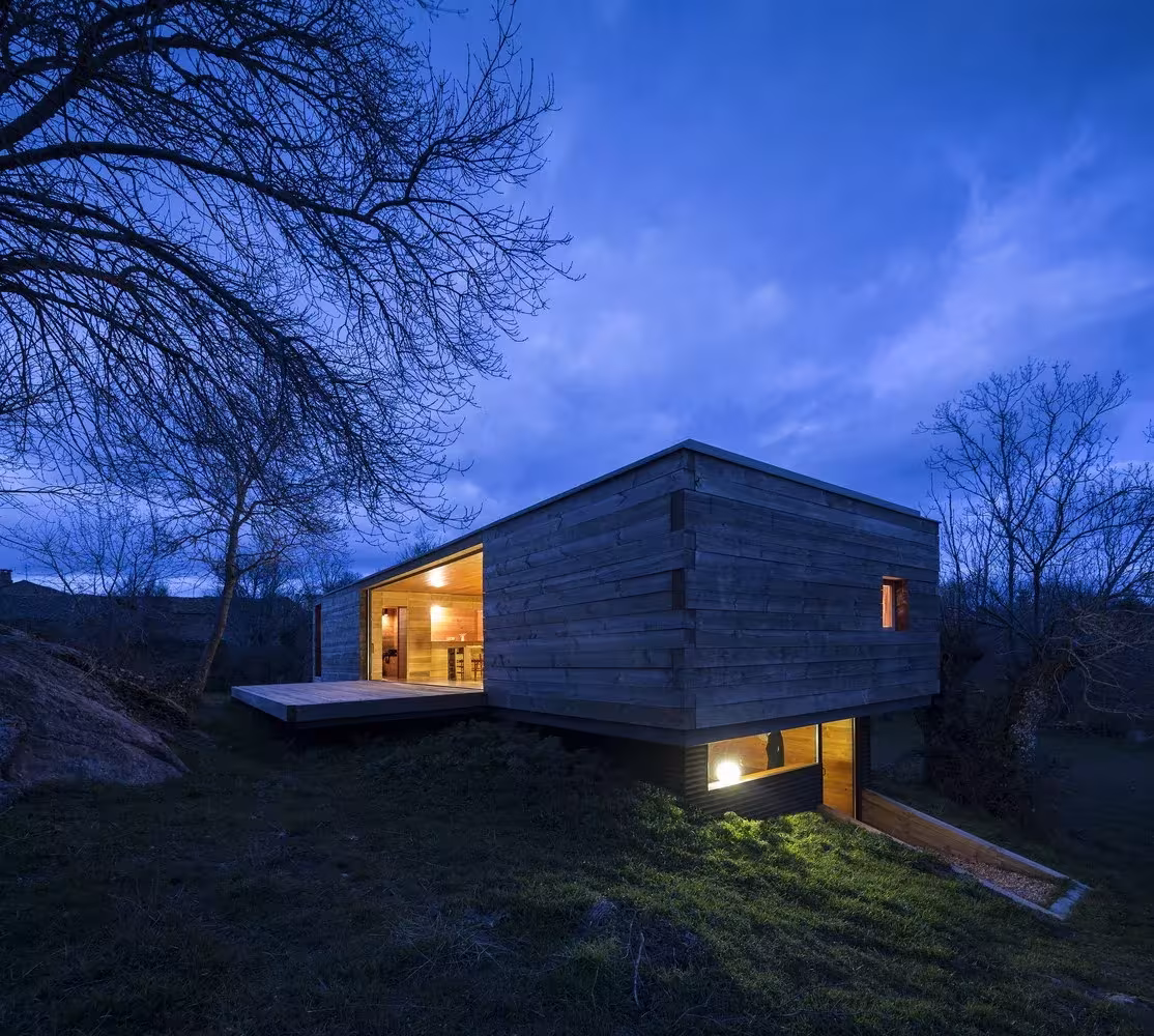 Vista nocturna de la Casa B de CH + QS arquitectos, una caja iluminada sobre el prado de Berrocal